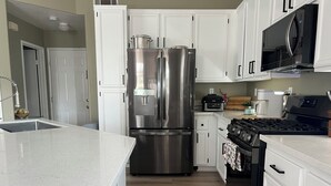 A modern kitchen with white cabinetry, stainless steel appliances, and a granite countertop. - Cozy 1-bedroom house in superb Valley Center with AC (Valley Center)