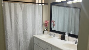 A bathroom with a white sink, mirror, and light fixture. - Cozy 1-bedroom house in superb Valley Center with AC (Valley Center)