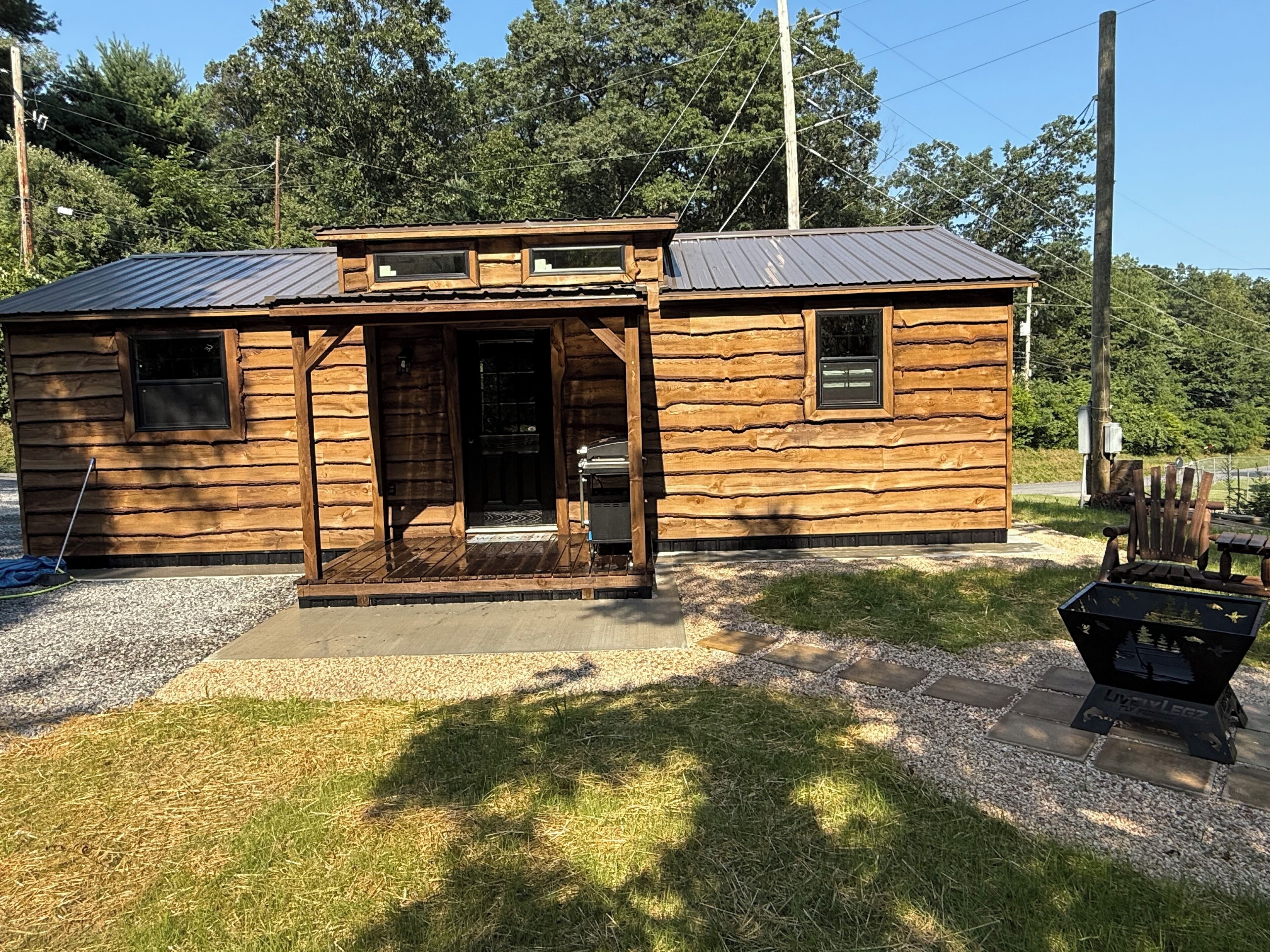 Une petite cabane en bois avec un toit en métal, une porte d’entrée et un petit porche.