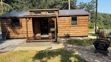 Une petite cabane en bois avec un toit en métal, une porte d’entrée et un petit porche.
