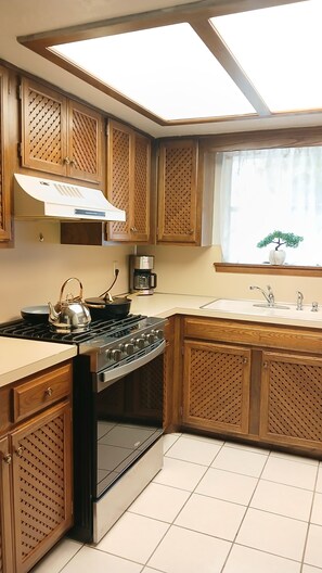 Una cocina con armarios de madera, estufa, hervidor y cafetera.