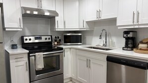 A modern kitchen with white cabinets, stainless steel appliances, and a dishwasher. - New, Cozy 1-Bed Room, Bsm Suite. with AC in Beautiful Edmonton, Prívate Entry. (Edmonton)