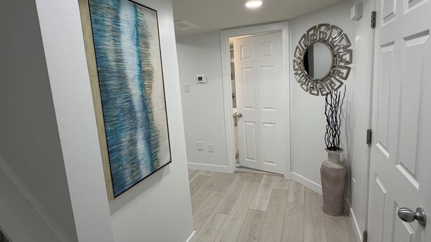 A hallway with a white door, a framed abstract painting, a decorative mirror, and a textured vase. - New, Cozy 1-Bed Room, Bsm Suite. with AC in Beautiful Edmonton, Prívate Entry. (Edmonton)