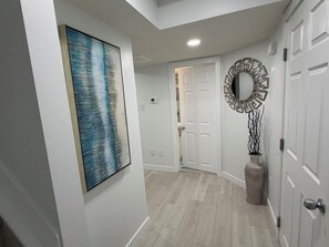 A hallway with a white door, a framed abstract painting, a decorative mirror, and a textured vase. - New, Cozy 1-Bed Room, Bsm Suite. with AC in Beautiful Edmonton, Prívate Entry. (Edmonton)