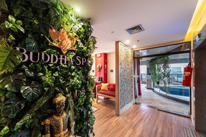 A room with a Buddha statue, a red sofa, and a view of a pool through a glass door. - Studio on Faria Lima With Pool and Spa - Bt1110 (São Paulo)