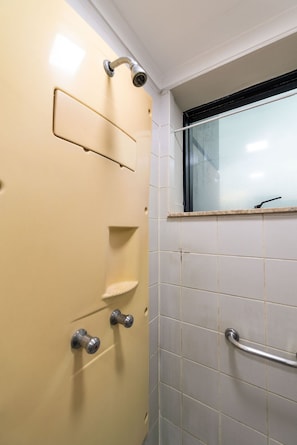 A bathroom with a white tiled wall, a window, a shower, and a door with a handle and a lock. - Studio on Faria Lima With Pool and Spa - Bt1110 (São Paulo)