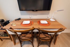 A dining table set with plates, cutlery, and glasses, with a television above and a lamp to the side. - Studio on Faria Lima With Pool and Spa - Bt1110 (São Paulo)