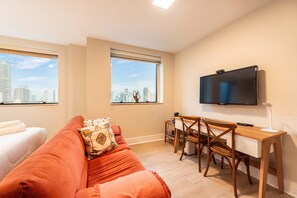 A room with a bed, a sofa, a desk with a chair, a TV, and a window with a city view. - Studio on Faria Lima With Pool and Spa - Bt1110 (São Paulo)