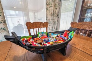 A dining table with a wicker chair filled with assorted snacks. - 3BR Vegas Home Jacuzzi Suite • BBQ • Pet Friendly (Las Vegas)