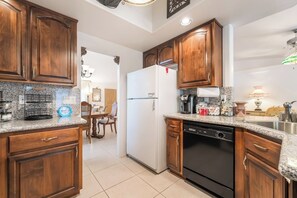 A kitchen with wooden cabinets, granite countertops, a dishwasher, and a refrigerator. - 3BR Vegas Home Jacuzzi Suite • BBQ • Pet Friendly (Las Vegas)
