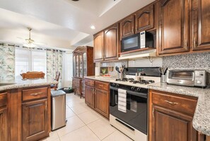 A kitchen with wooden cabinets, a microwave, a stove, and a toaster. - 3BR Vegas Home Jacuzzi Suite • BBQ • Pet Friendly (Las Vegas)