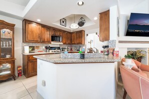 Una cocina moderna con encimeras de granito, armarios de madera y una isla central.