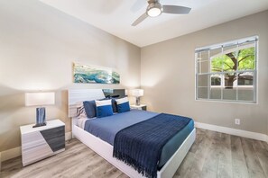 Ein Schlafzimmer mit einem Bett, zwei Nachttischen, einem Deckenventilator, einem Fenster mit Blick und einem Bild an der Wand.