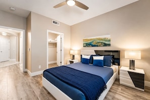 Ein Schlafzimmer mit einem Bett, Nachttischen, einem Deckenventilator und einem Bild an der Wand.