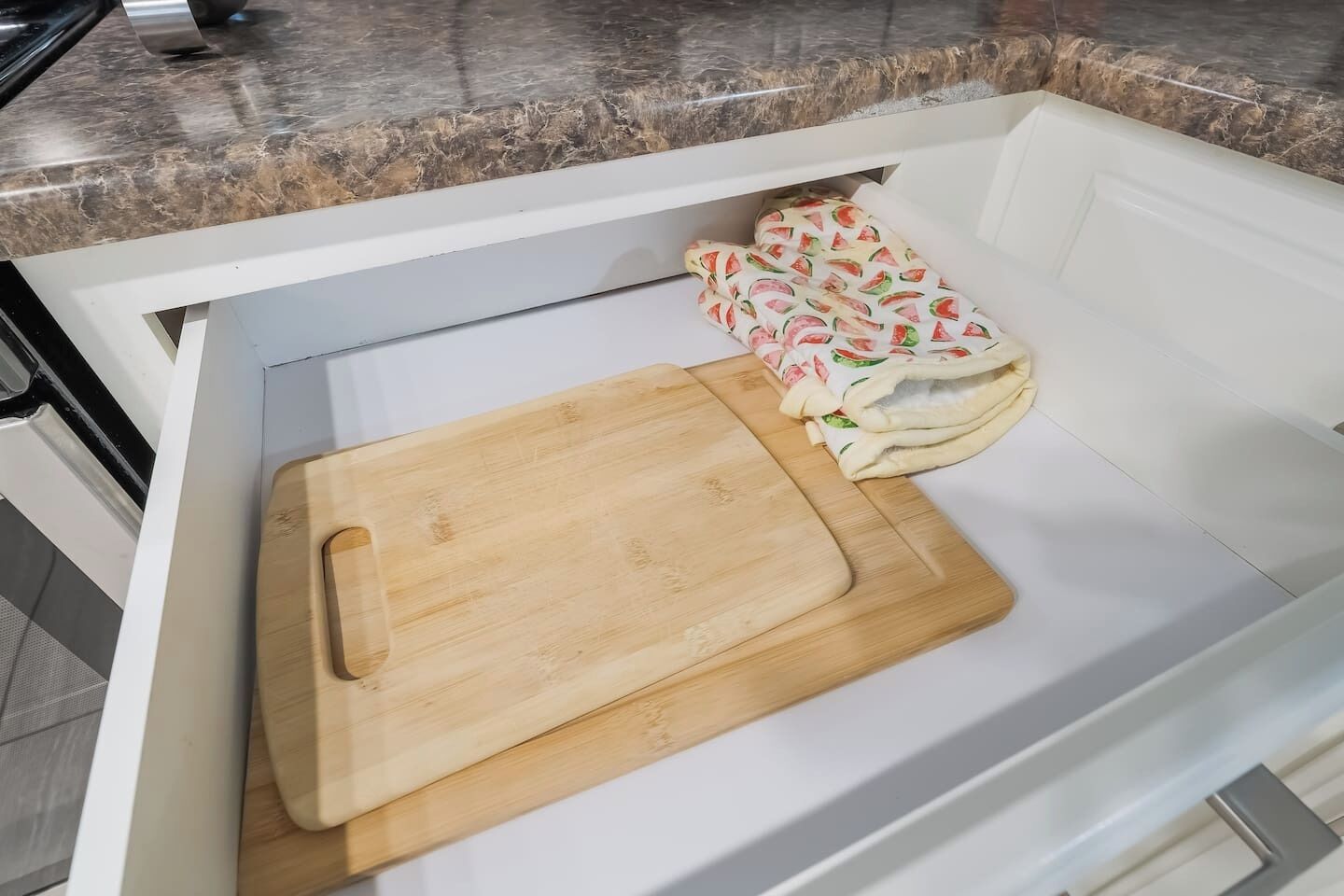 Eine Küchenschublade mit einem Holzschneidebrett und einem Stoff mit Wassermelonenmuster.