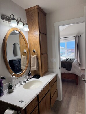 A bathroom with a wooden vanity, a large mirror, a sink, and a towel rack. - Barn Loft Stay with horses on 10 acres near Lewiston, ID (Lewiston)