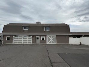 A two-story building with a garage, a small window, and a door with a wreath. - Barn Loft Stay with horses on 10 acres near Lewiston, ID (Lewiston)