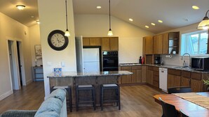 A modern kitchen with wooden cabinets, a central island, and a dining area with a table and chairs.