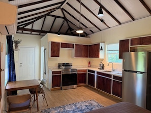 A kitchen with wooden cabinets, a stainless steel refrigerator, a stove, and a coffee maker.
