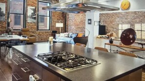 A kitchen with a central island, a stove, and a brick wall.