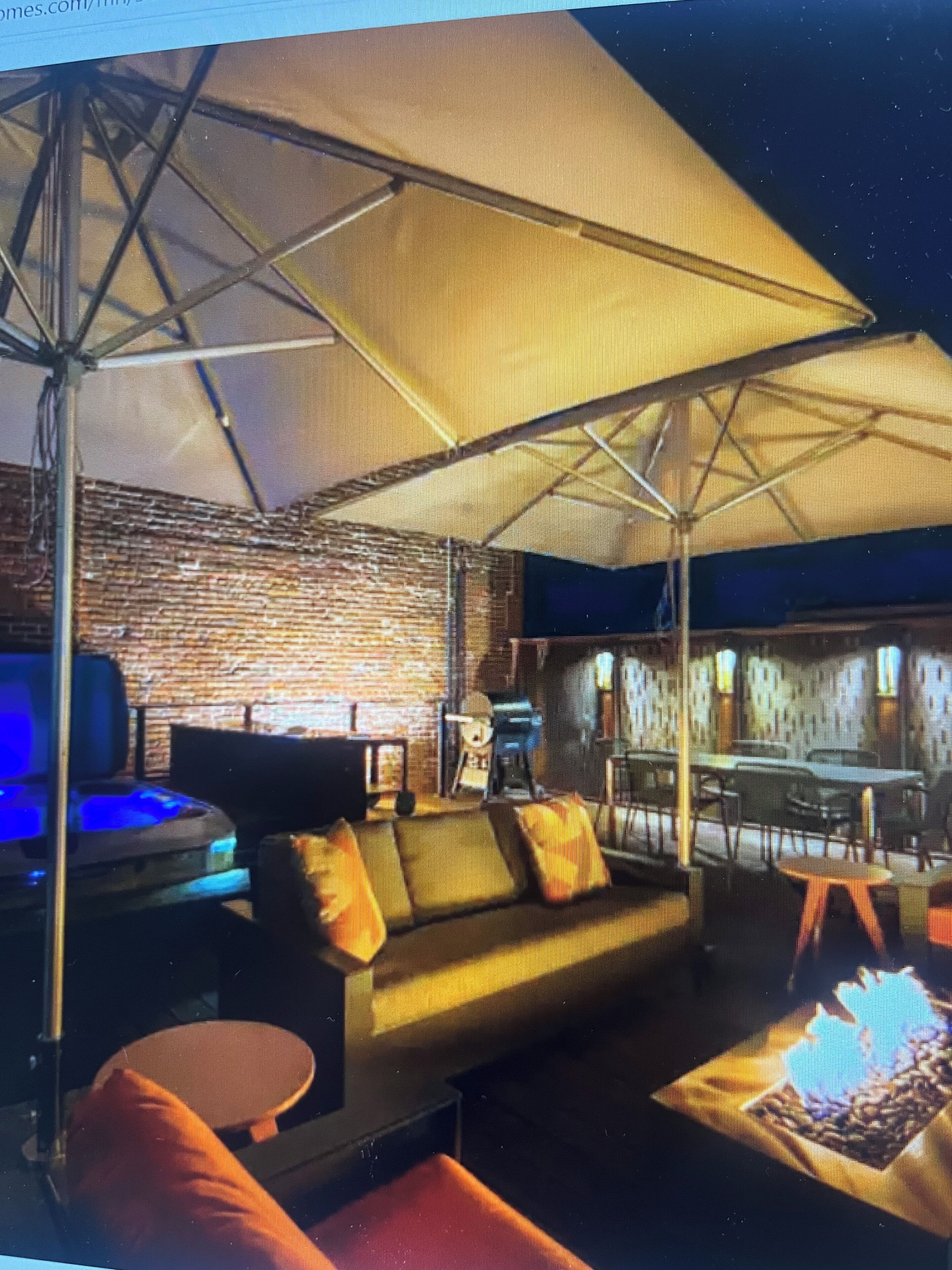Un'area lounge moderna con un divano, poltrone, un tavolino da caffè e un ombrellone grande.