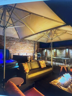 Ein stilvoller Lounge-Bereich mit einer Couch, Sesseln, einem Couchtisch und einem großen Sonnenschirm.