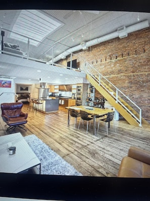 A spacious loft with a kitchen, dining area, and a staircase leading to an upper level.