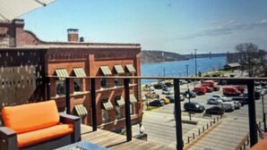 A deck with outdoor furniture, a fire feature, and a view of a parking lot and buildings.