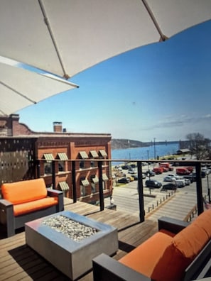 A deck with outdoor furniture, a fire feature, and a view of a parking lot and buildings.