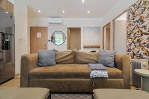 Ein modernes Wohnzimmer mit einer Couch, einer Kaffeemaschine, einer Heizung und einem Bild an der Wand.