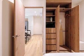 Ein Schlafzimmer mit einem Holzkleiderschrank, einem Bett und einem Schreibtisch mit Stühlen.