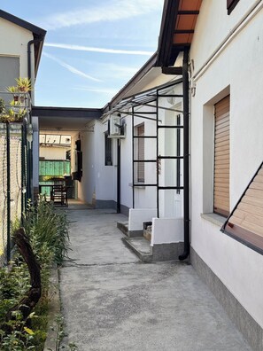 A narrow alleyway with a covered outdoor seating area, a staircase, and a green fence. - Vrbo Property (Staranzano)