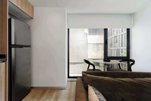 Eine moderne Küche mit Einbaukühlschrank, einem Holzkasten und einer Glastür, die auf einen Balkon mit Tisch und Stühlen führt.