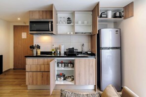 Une cuisine moderne avec des meubles en bois, un réfrigérateur en acier inoxydable, un four à micro-ondes et un four encastré.