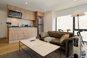Un espacio habitable compacto con kitchenette, un sofá, una mesa y un calentador.