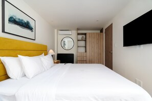 Ein Hotelzimmer mit einem Bett, einem gelben Kopfteil, einem Flachbildfernseher, einem Schrank und einem gerahmten Bild an der Wand.
