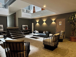 Ein modernes Wohnzimmer mit einer Couch, Sesseln, einem Couchtisch, einer Treppe und einer Pflanze.