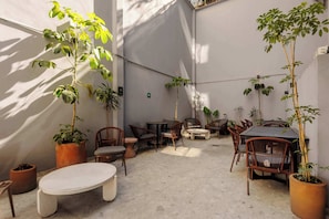 An outdoor seating area with tables and chairs, surrounded by potted plants. - w* | Upscale 1BR w/ AC in the Heart of Cuauhtémoc (Ciudad de México)