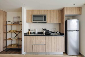 Eine moderne Küche mit Holzschränken, einer Edelstahl-Mikrowelle und einem Kühlschrank.