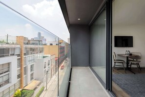 Ein Balkon mit Blick auf die Stadt, einem Flachbildfernseher und einem kleinen Tisch mit Stühlen.