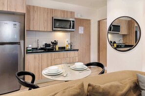 A compact kitchen with a microwave, stove, and refrigerator. There is a dining table with chairs and a round mirror on the wall. - w* | Warm 2BR  w/ AC in the Heart of Cuauhtémoc (Ciudad de México)