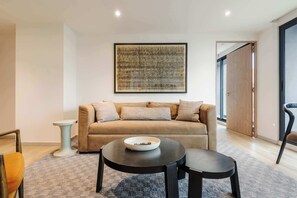Un salon moderne avec un canapé, une table basse et une œuvre d’art abstraite encadrée accrochée au mur.