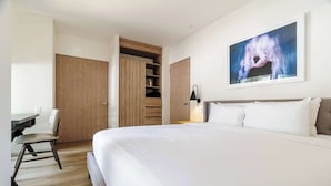 Ein Schlafzimmer mit einem großen Bett, einem Schreibtisch, einem Stuhl, einem Kleiderschrank und einem Bild an der Wand.