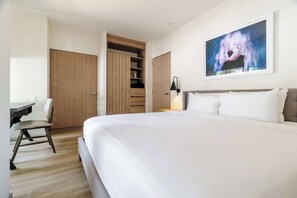 Ein Schlafzimmer mit einem großen Bett, einem Schreibtisch, einem Stuhl, einem Kleiderschrank und einem Bild an der Wand.