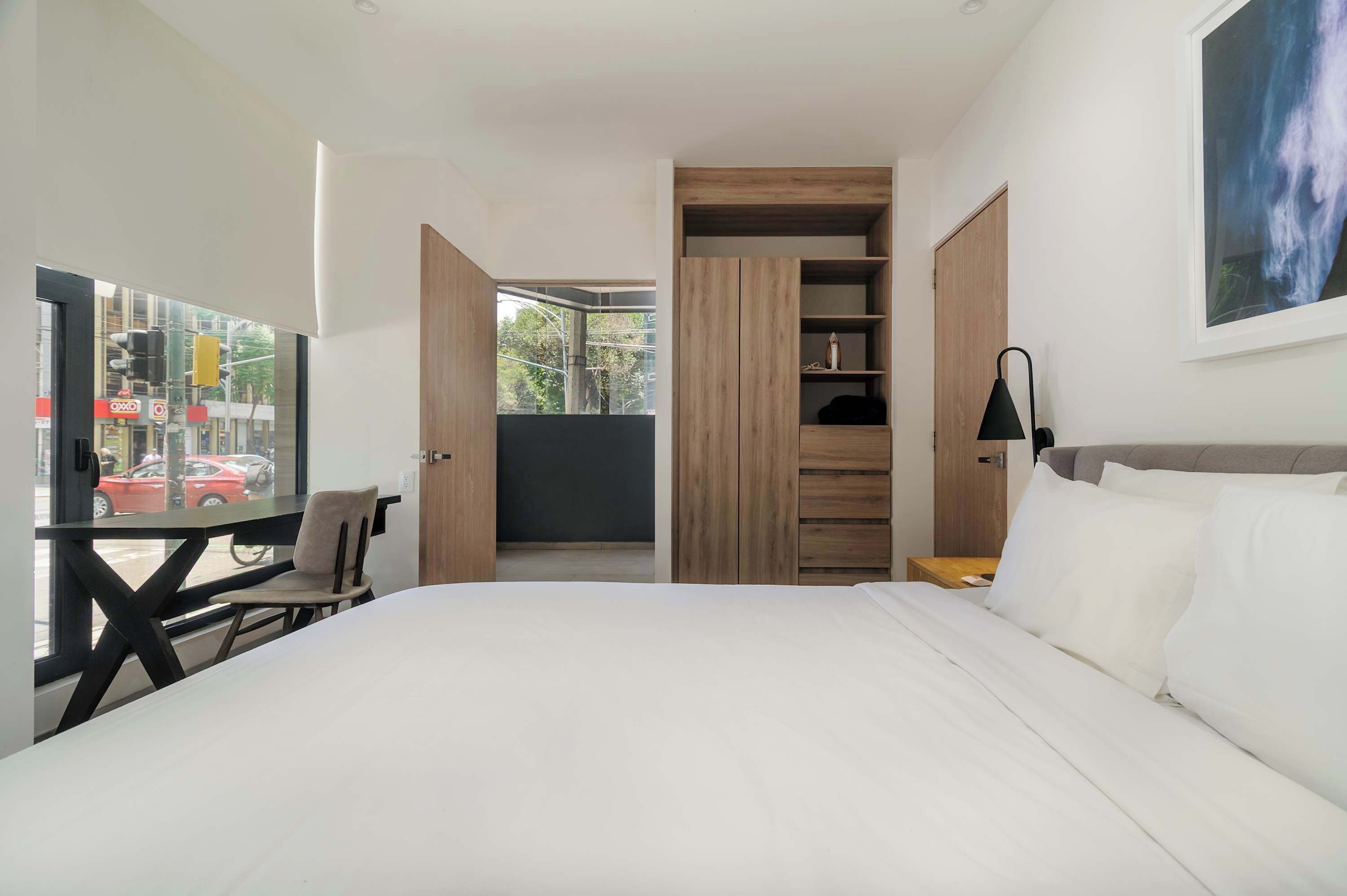 Een moderne slaapkamer met een bed, een bureau en een stoel. Er is uitzicht naar buiten door een raam.