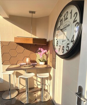 Een moderne keuken met een grote wandklok, barstoelen en een backsplash met geometrische patronen.