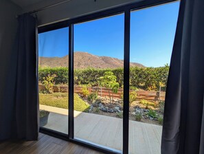 Ein Zimmer mit großen Schiebeg lassfenstern, die zu einer angelegten Außenanlage mit Bergblick führen.