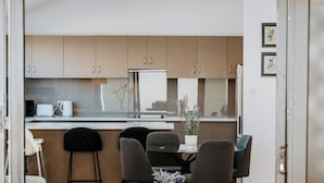 Eine moderne Küche mit Essbereich, ausgestattet mit einem Holztisch, Stühlen und einem Kühlschrank.