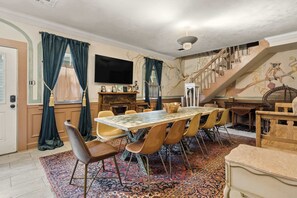 Een eethoek met een marmeren tafel, stoelen, een open haard en een trap met een muurschildering.
