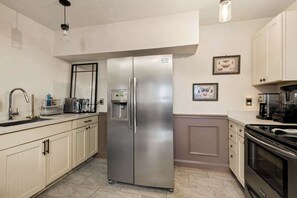 Uma cozinha moderna com geladeira de aço inoxidável, forno embutido e cafeteira.